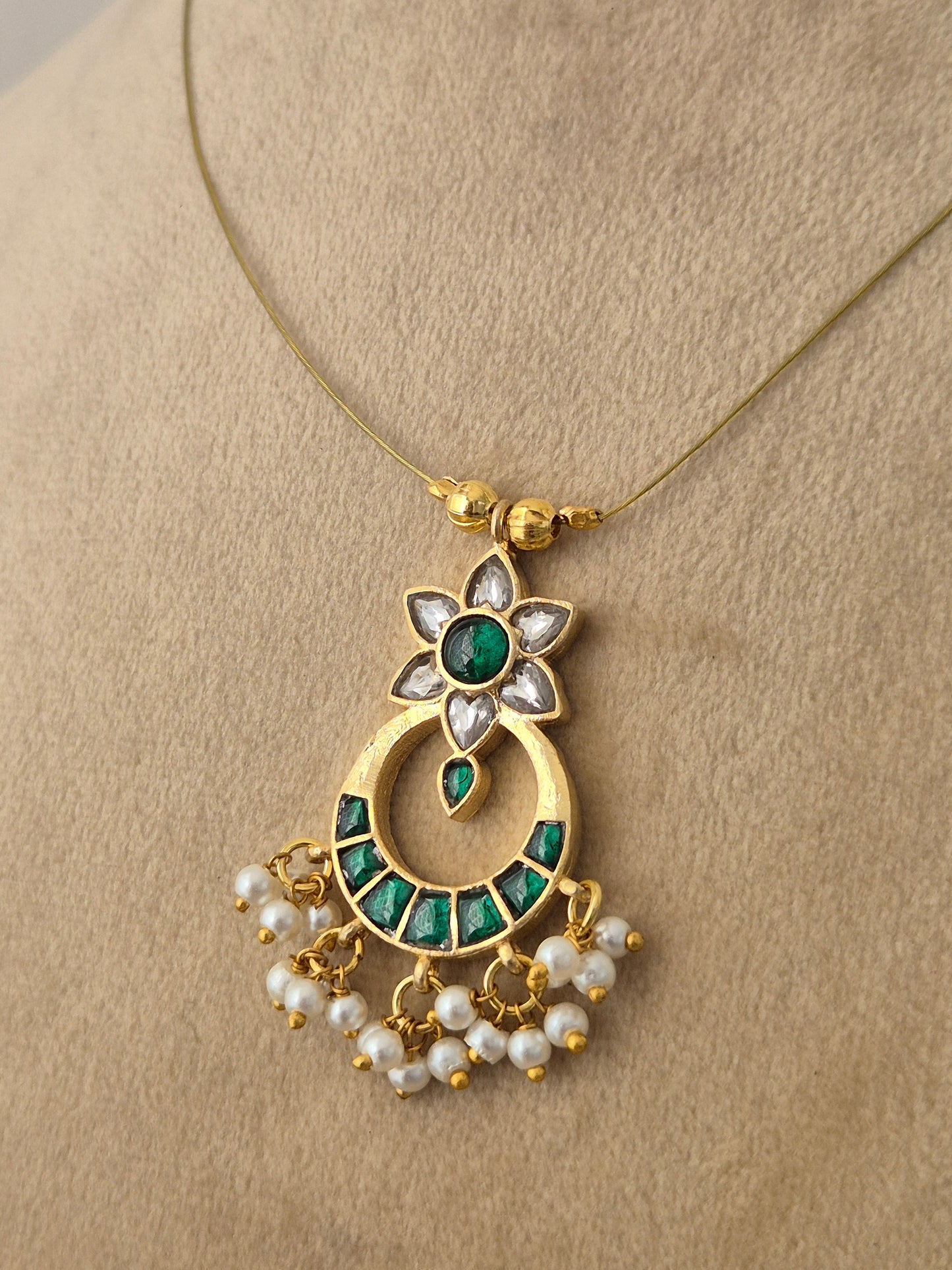 Modern Indian aesthetic invisible chain necklace with a traditional floral-motif crescent pendant in gold,, and green by naitri.in