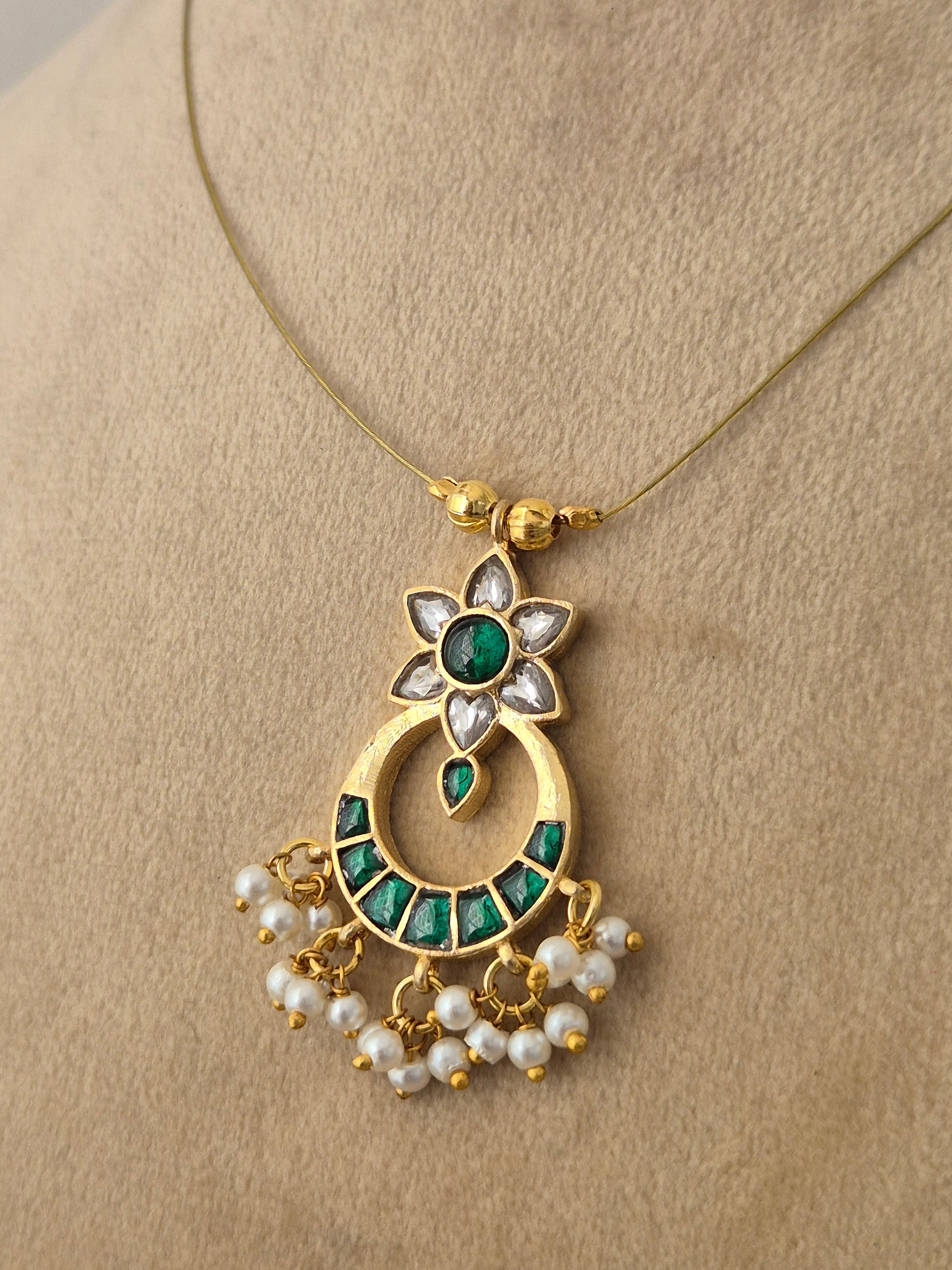 Modern Indian aesthetic invisible chain necklace with a traditional floral-motif crescent pendant in gold,, and green by naitri.in
