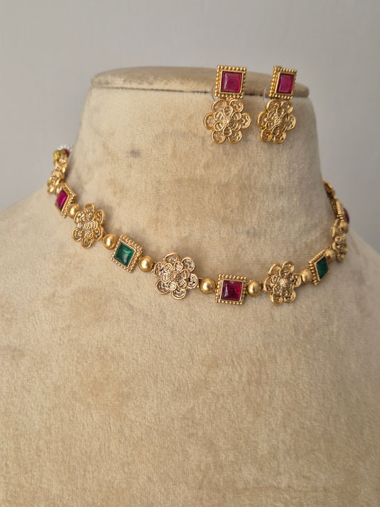 Antique gold-polished floral choker set with ruby-red and emerald-green stone embellishments, part of the Naitri golden ethnic jewellery collection by naitri.in