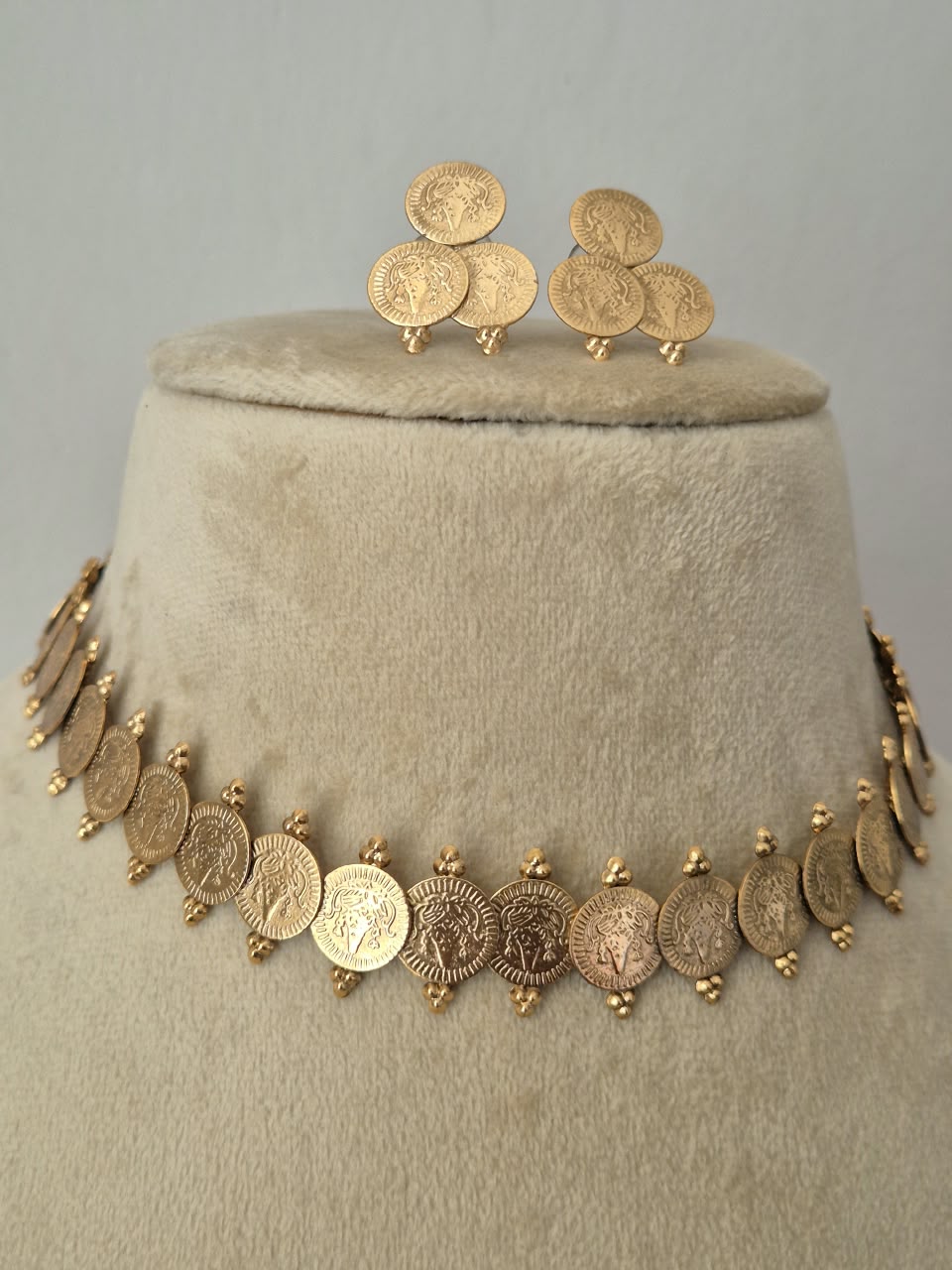 Traditional gold coin dangle earrings with intricate embossed detailing, paired with a matching choker necklace by naitri.in