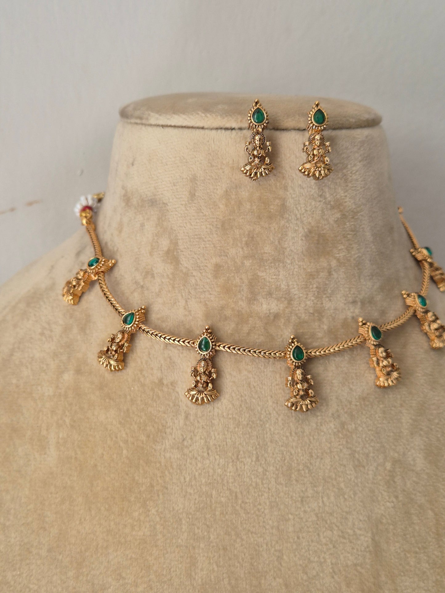 Antique gold-plated ethnic choker set featuring delicate dangling pendants with tiny emerald- green  stone accents with coordinating hanging stud earrings by naitri.in