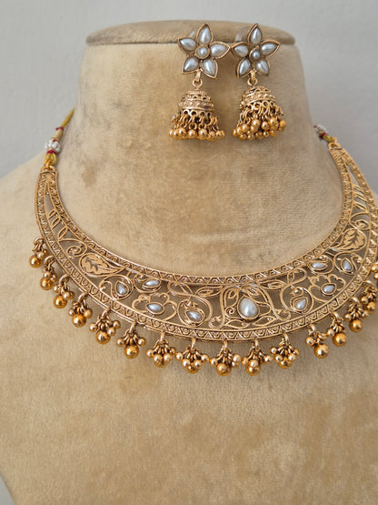 Traditional Indian antique-finish brass necklace set showcasing elaborate floral engravings, white  gemstone embellishments, and a structured collar silhouette with delicate gold pearl drops by naitri.in