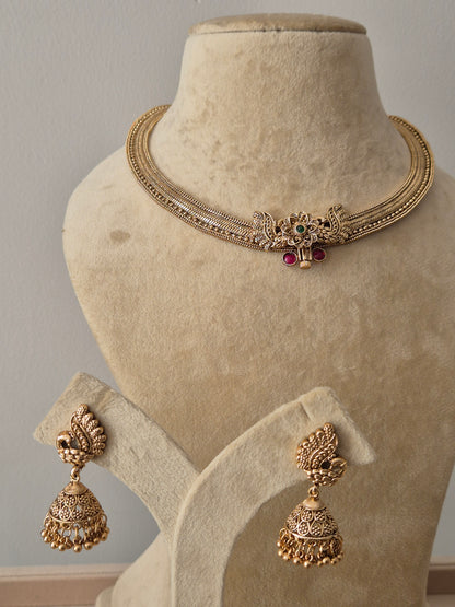 Handcrafted temple-style golden necklace set featuring intricate bird carvings and vibrant stone accents by naitri.in
