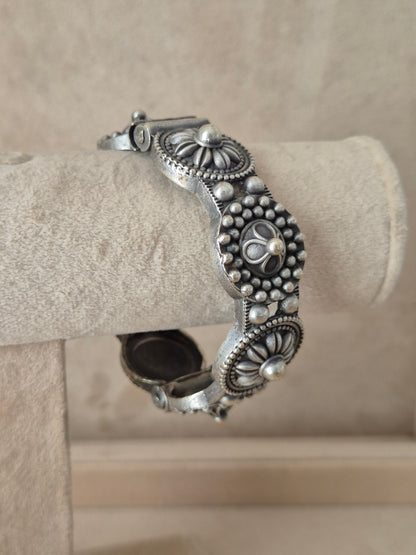Close-up of Naitri Nafisa premium silver oxidized bangle bracelet with traditional Indian style textured leaf and flower metalwork.