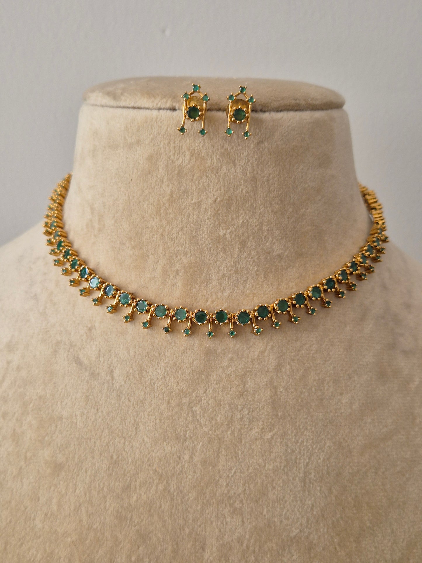 Gold-toned choker necklace and matching stud earrings with green stone embellishments by naitri.in