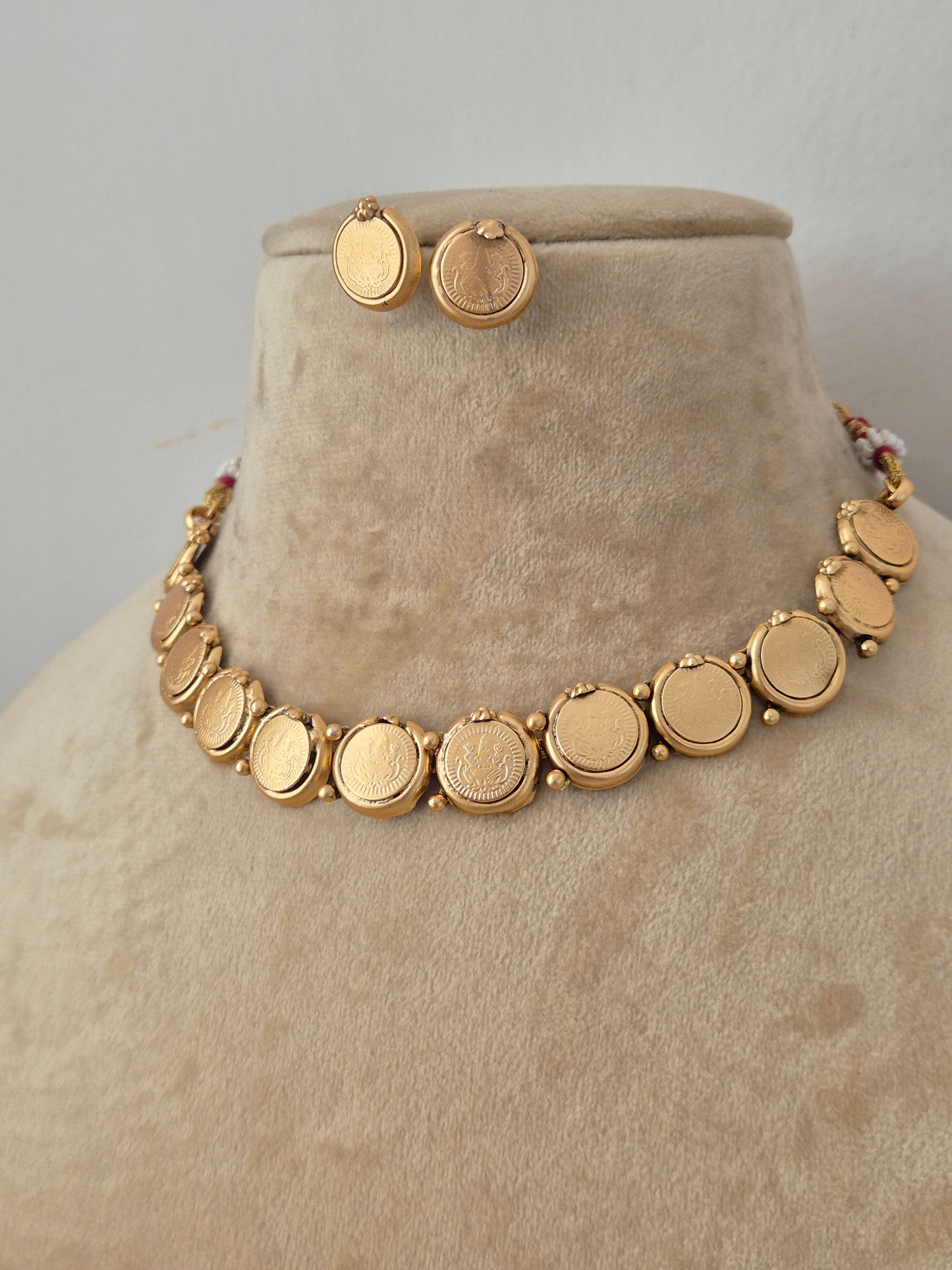Gold-plated ethnic choker necklace featuring a continuous row of smooth, polished circular coin pendants, shown on a mannequin with coordinating round button stud earrings by naitri.in