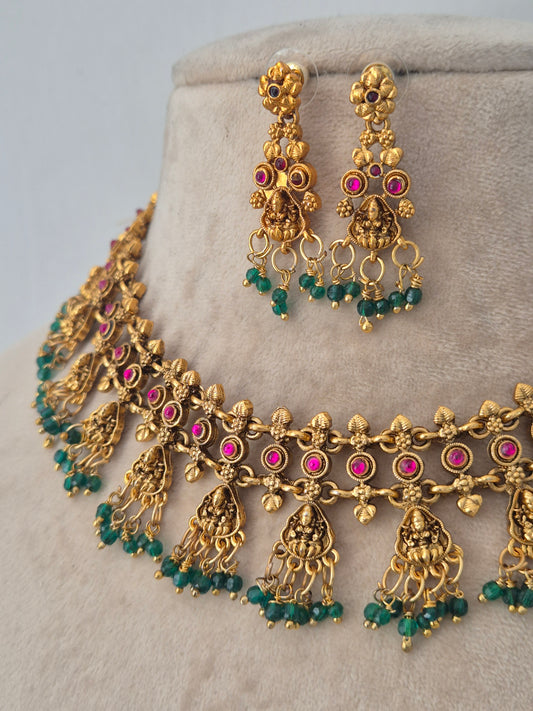 Gold-toned traditional jewelry set featuring a necklace and matching earrings with pink gemstone accents and green bead fringe by naitri
