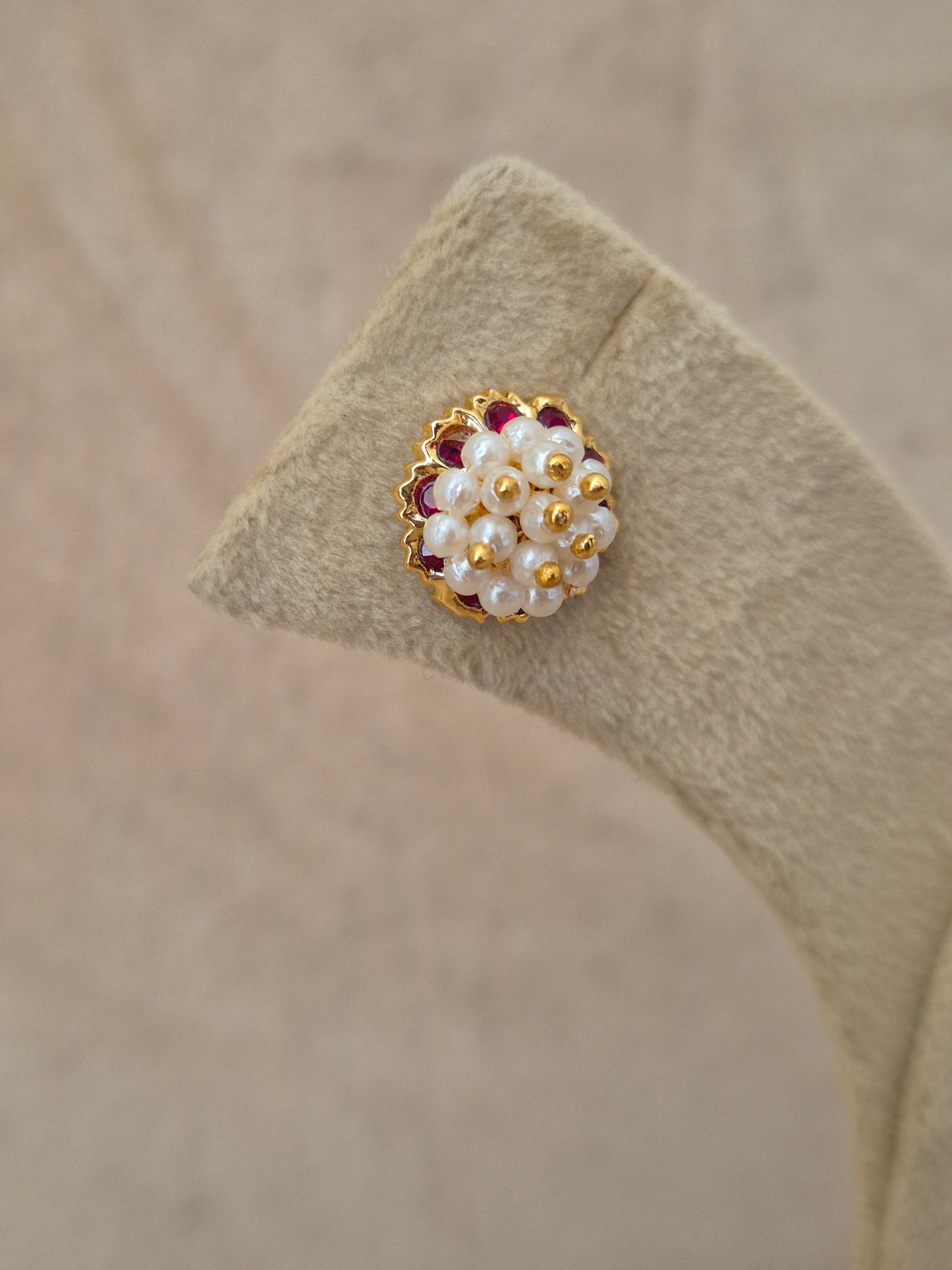 Close-up of Naitri Niyati premium gold ethnic earrings showcasing traditional Indian Jhumka craftsmanship with clustered pearl details and ruby red stone accents by naitri.in