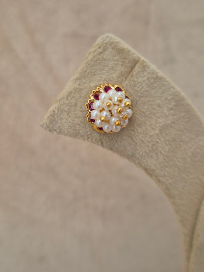 Close-up of Naitri Niyati premium gold ethnic earrings showcasing traditional Indian Jhumka craftsmanship with clustered pearl details and ruby red stone accents by naitri.in