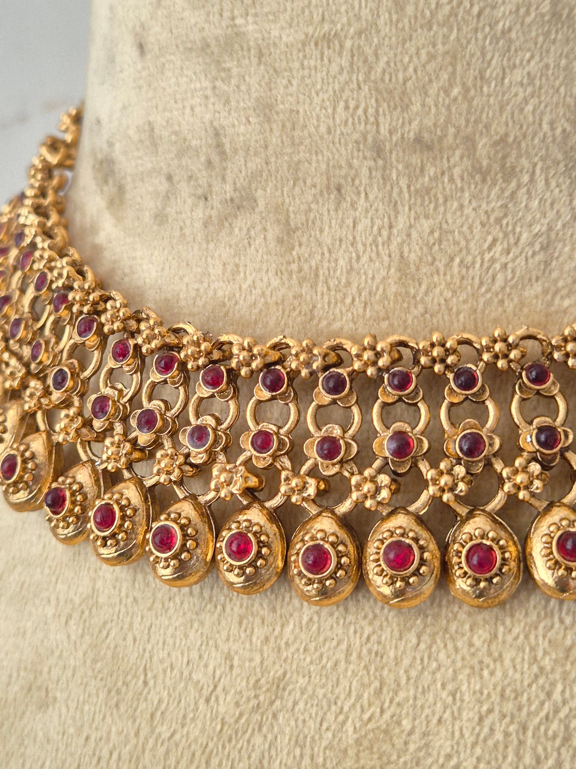 Gold-toned traditional jewelry set featuring a statement collar necklace exhibits an intricate, polished multi-layered metallic texture with classic Indian aesthetic craftsmanship by naitri.in