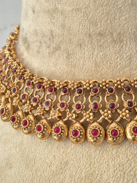 Gold-toned traditional jewelry set featuring a statement collar necklace exhibits an intricate, polished multi-layered metallic texture with classic Indian aesthetic craftsmanship by naitri.in