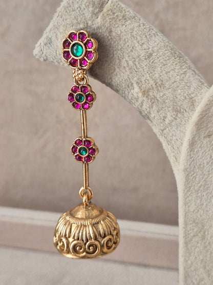 Gold-plated long dangling jhumka earrings featuring a vertical drop of ruby-red and emerald-green stone clusters leading to an intricate bell-shaped dome by naitri.in