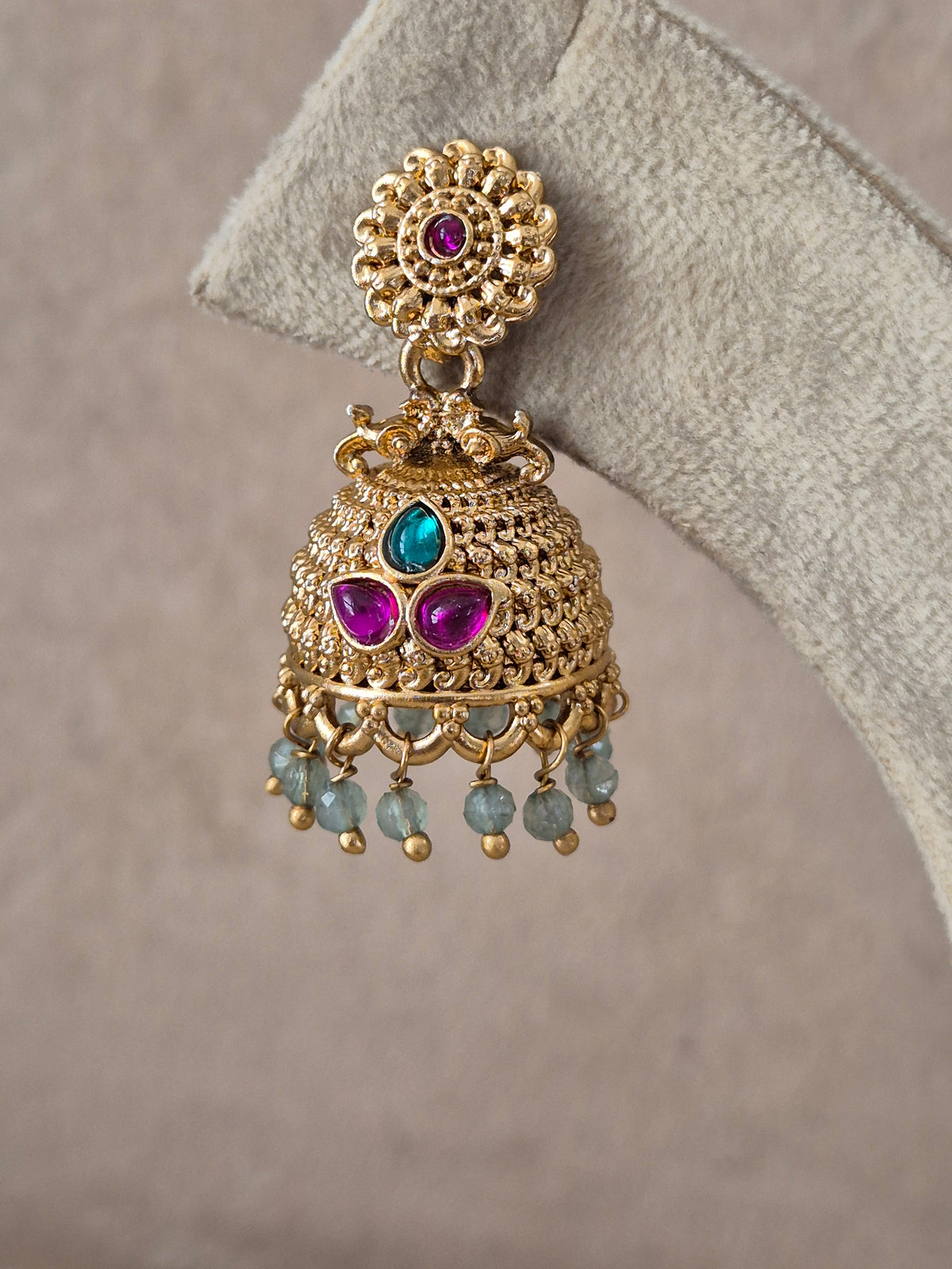 Pair of intricate brass alloy dangle earrings featuring floral studs, bell-shaped jhumkas with colorful red and green stone highlights, and delicate bead drops by naitri.in