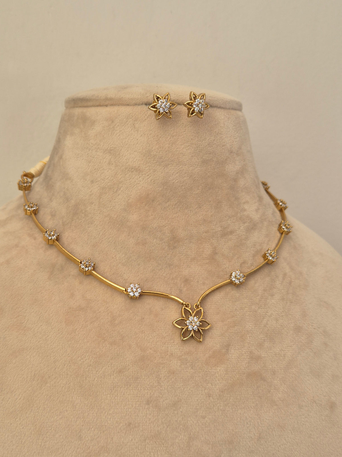 Minimalist gold and crystal floral necklace and stud earrings set by naitri.in