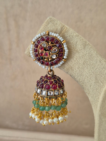 Close-up of Naitri Poorvi premium gold ethnic earrings showcasing traditional Indian Jhumka craftsmanship with vibrant pink and green embellishments and delicate pearl dangling beads by naitri.in