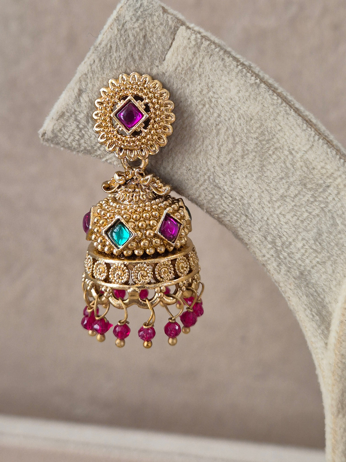 Pair of intricate brass alloy dangle earrings featuring floral studs, bell-shaped jhumkas with colorful red and green stone highlights, and delicate bead drops by naitri.in