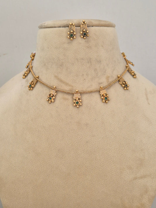 Traditional Indian gold-toned choker necklace with delicate hanging floral charms accented with green gemstones by naitri.in