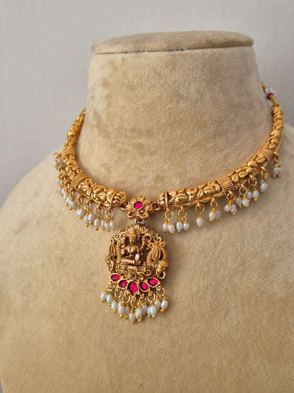 Traditional Indian antique-finish brass necklace set showcasing intricate floral metalwork, a deity-engraved central pendant, and rich white pearl cluster fringes from the Naitri Golden Ethnic Jewellery collection by naitri.in