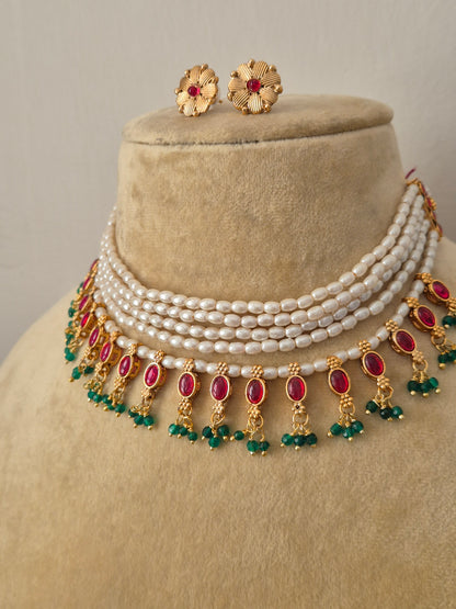 Traditional Indian antique gold-finish jewelry set showcasing a structured multi-strand pearl choker adorned with colorful gemstone drops and intricate floral stud earrings from the Naitri collection by naitri.in