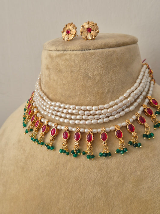 Traditional Indian antique gold-finish jewelry set showcasing a structured multi-strand pearl choker adorned with colorful gemstone drops and intricate floral stud earrings from the Naitri collection by naitri.in