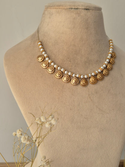 A handcrafted gold-plated choker featuring pearls and golden-rings between circular gold coin drops by  naitri.in