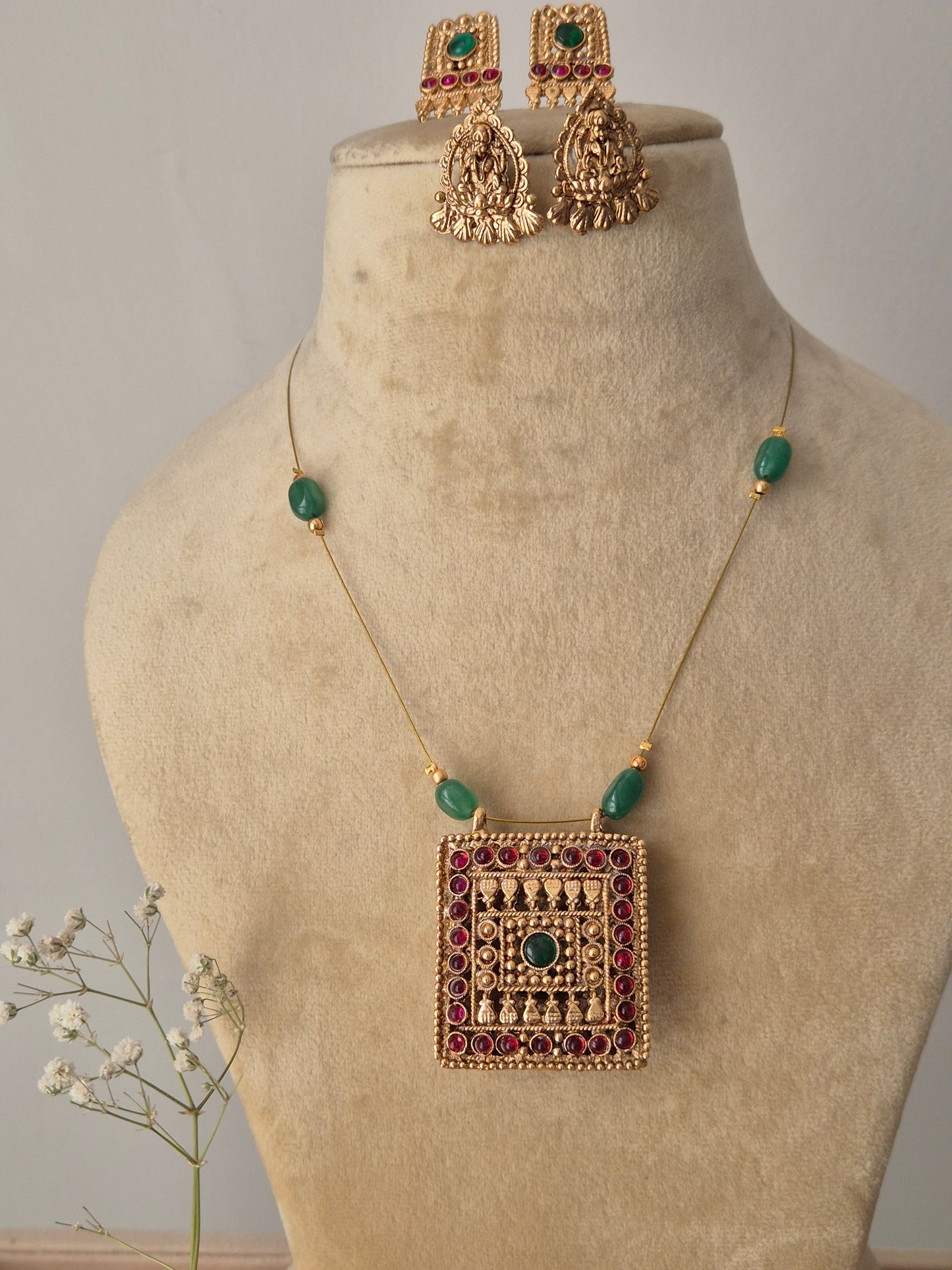 Gold-plated reversible pendant necklace and earring set with emerald and ruby-colored stones, reversible gold pendant necklace with red and green stones and matching traditional earrings by naitri.in