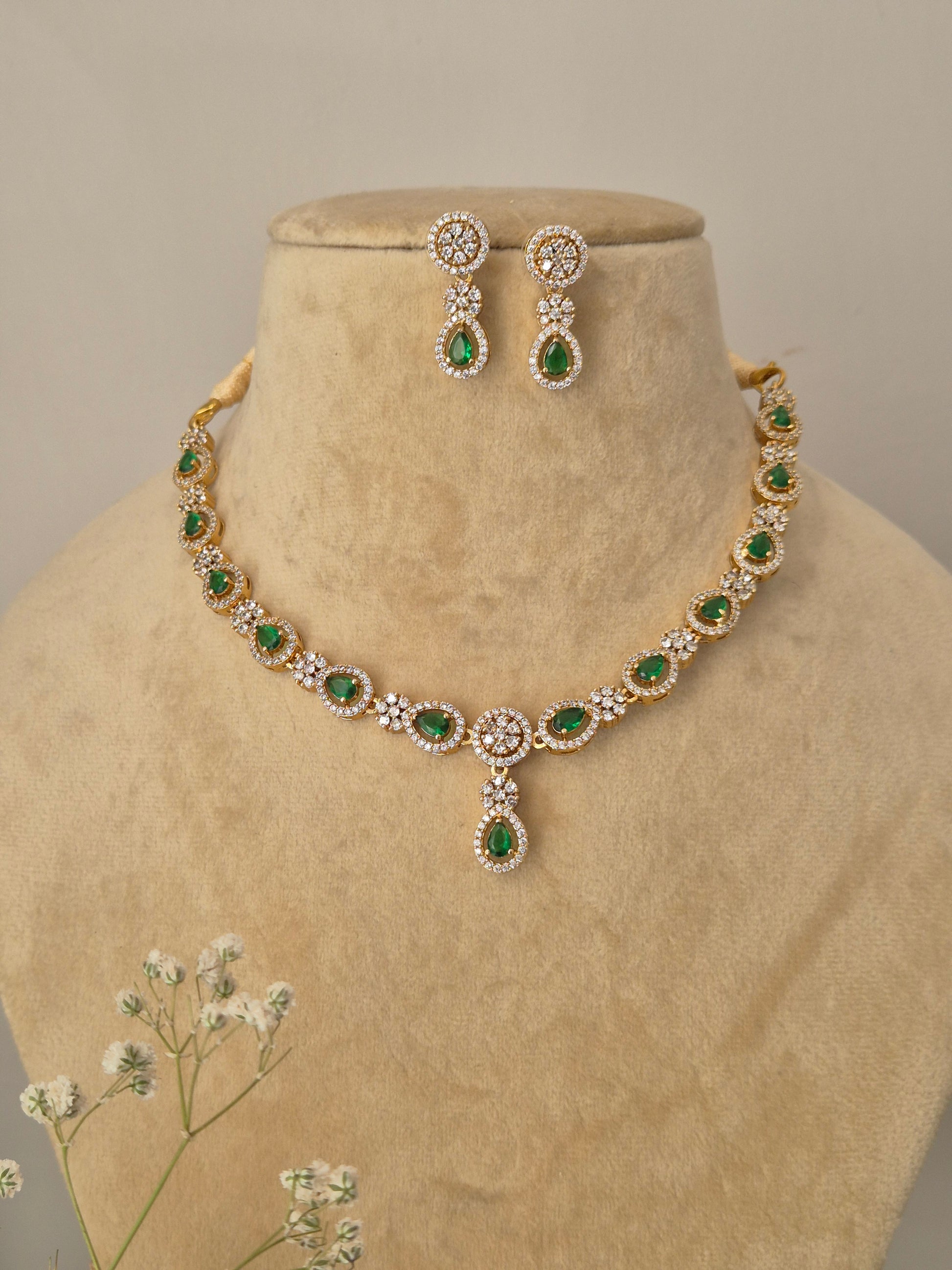 Minimalist golden chain necklace featuring alternating green teardrop stones and shimmering white AD clusters by naitri.in