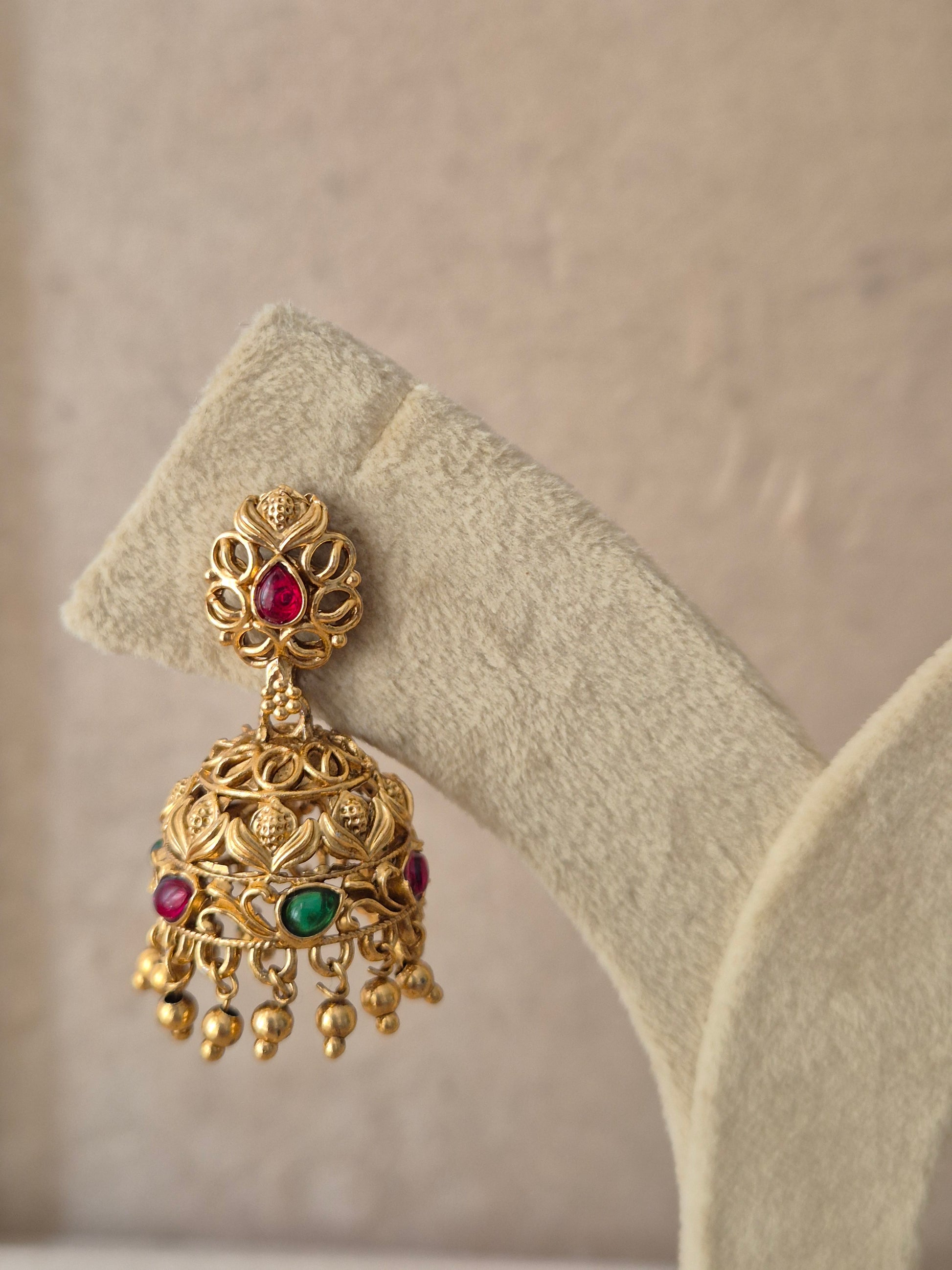 Antique gold-plated Samaya Jhumka earrings featuring ruby-colored stone accents by naitri.in
