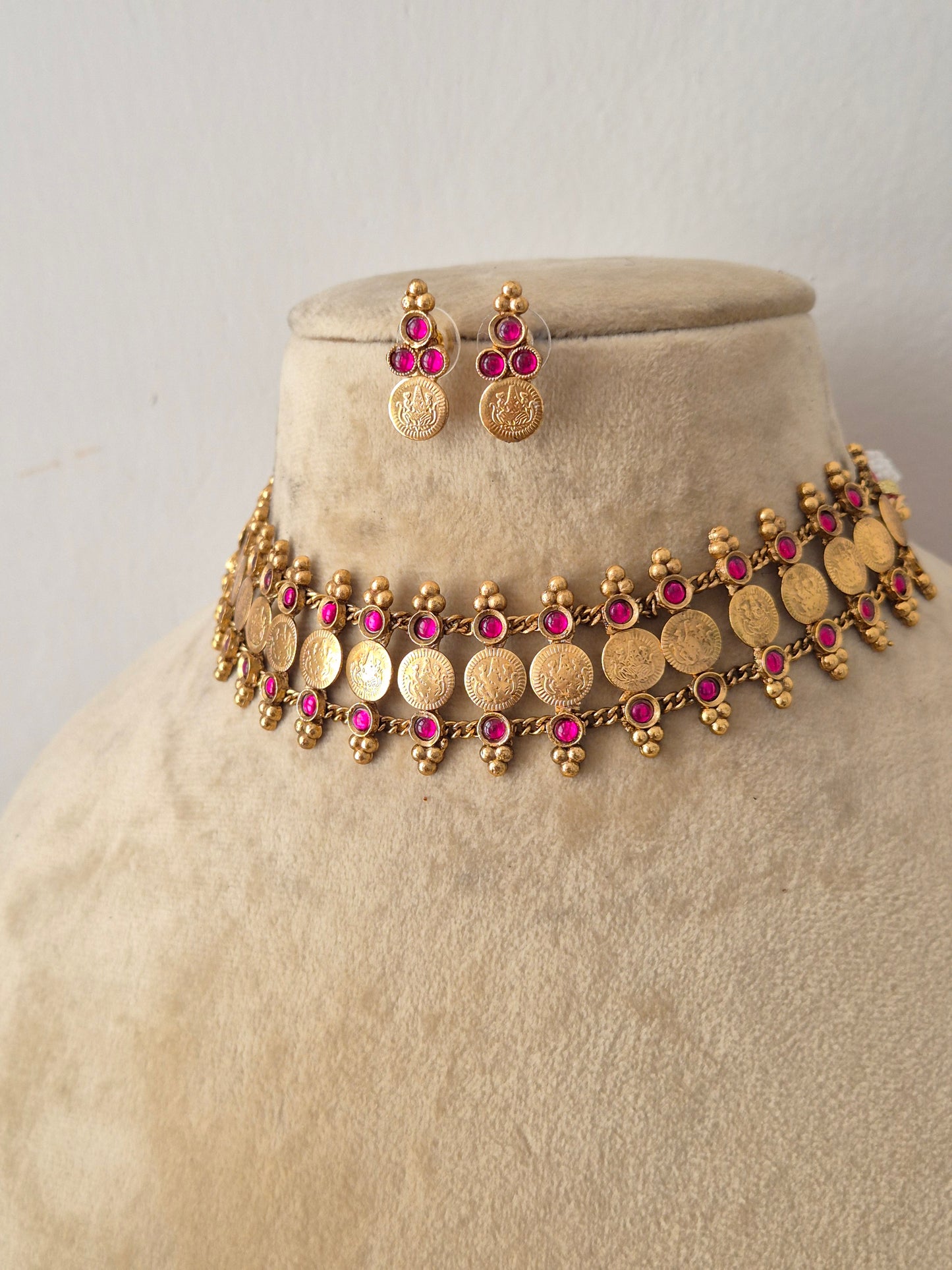 Modern Indian imitation jewelry set featuring an intricate golden brass alloy coin choker necklace with ruby-red gemstone accents, by naitri.in