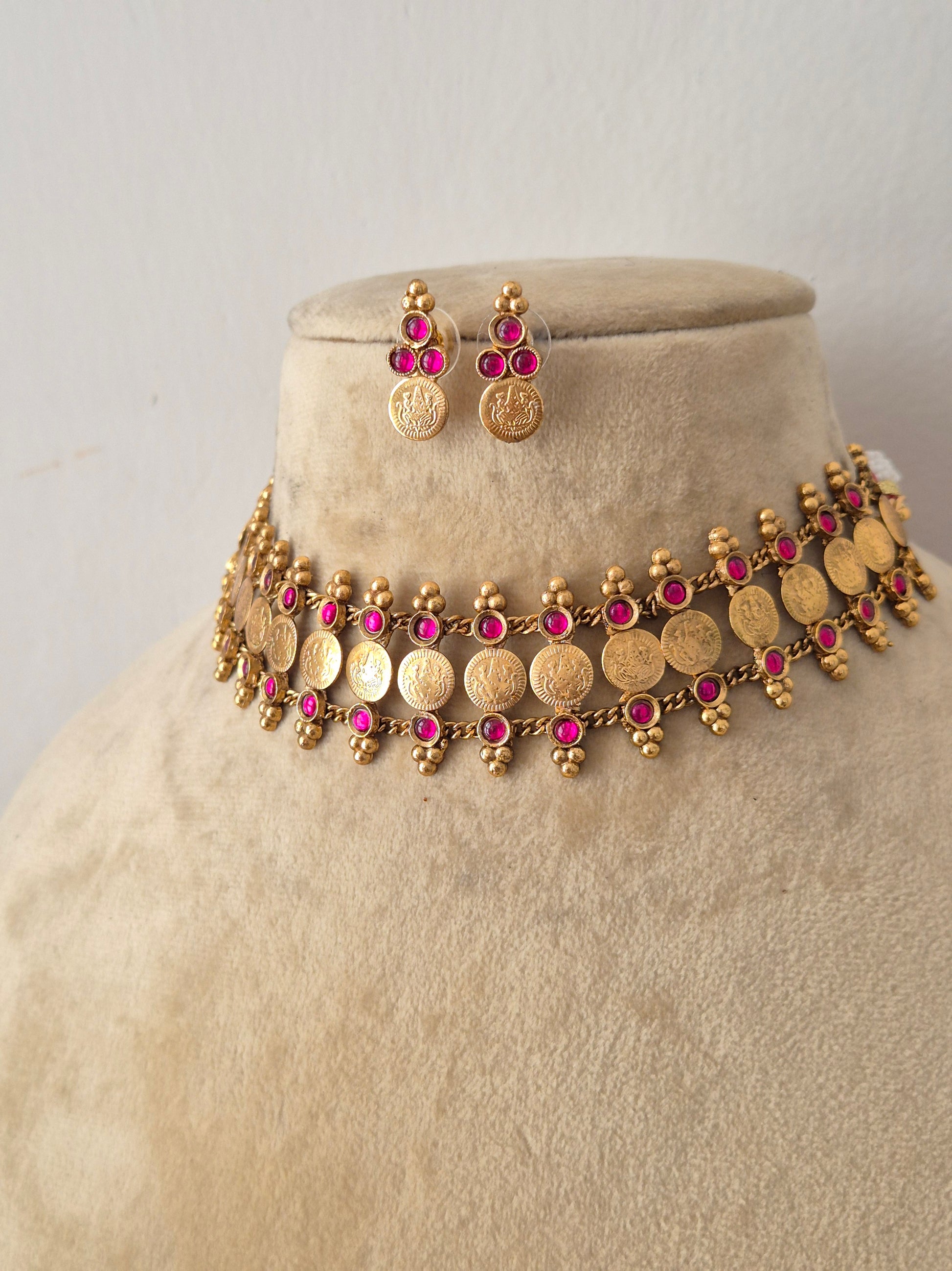 Modern Indian imitation jewelry set featuring an intricate golden brass alloy coin choker necklace with ruby-red gemstone accents, by naitri.in