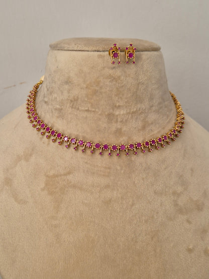 Handcrafted jewelry set in brass alloy with a polished golden finish and vibrant ruby-red stone accents by naitri.in