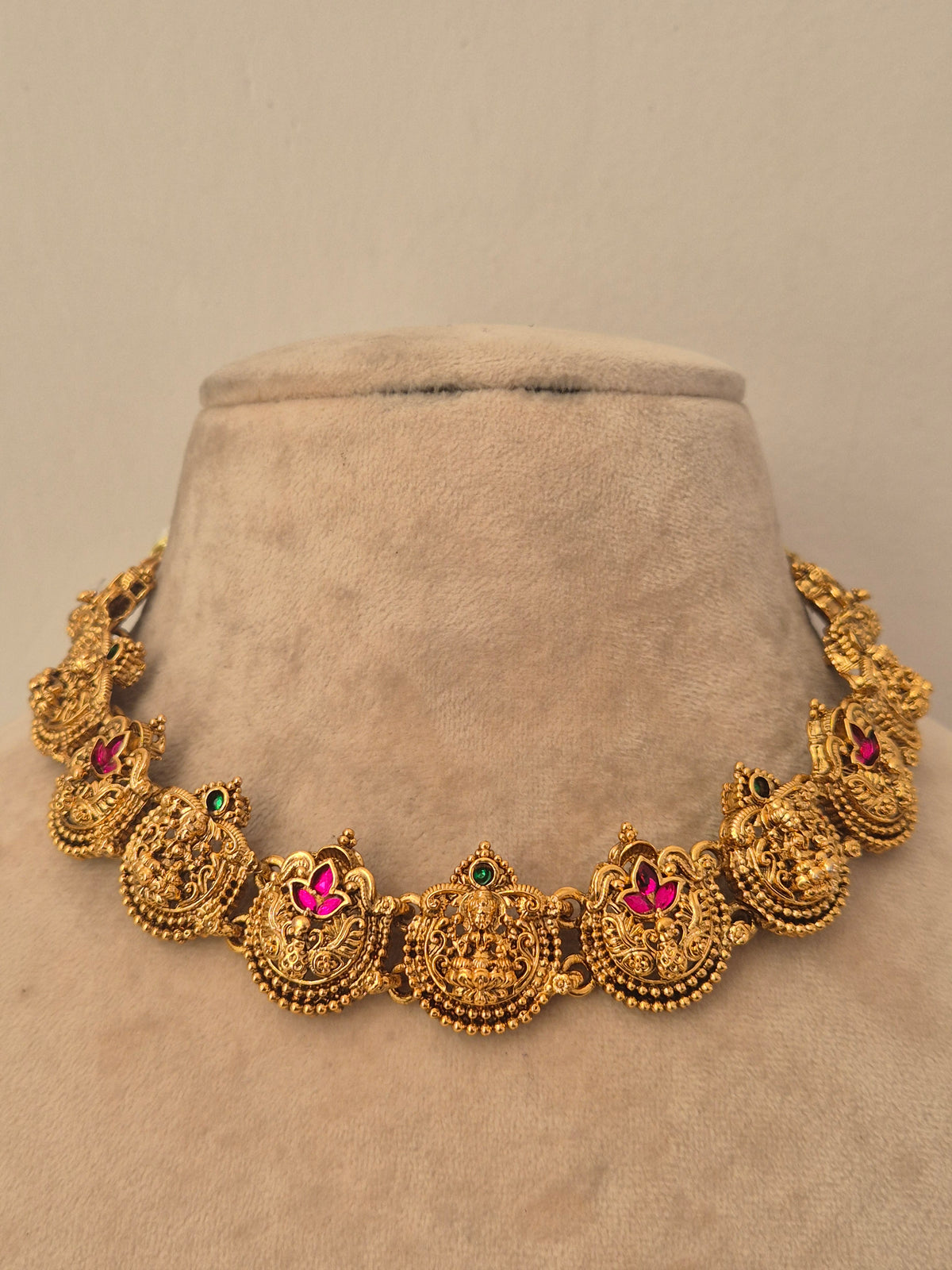Traditional gold temple choker necklace with round peacock motifs featuring pink ruby stone centers and small green gem accents, by naitri.in