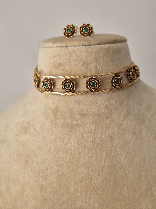 Antique gold-polished choker necklace featuring intricate metalwork and floral green stone accents, part of the Naitri Golden Ethnic Jewellery collection by naitri.in