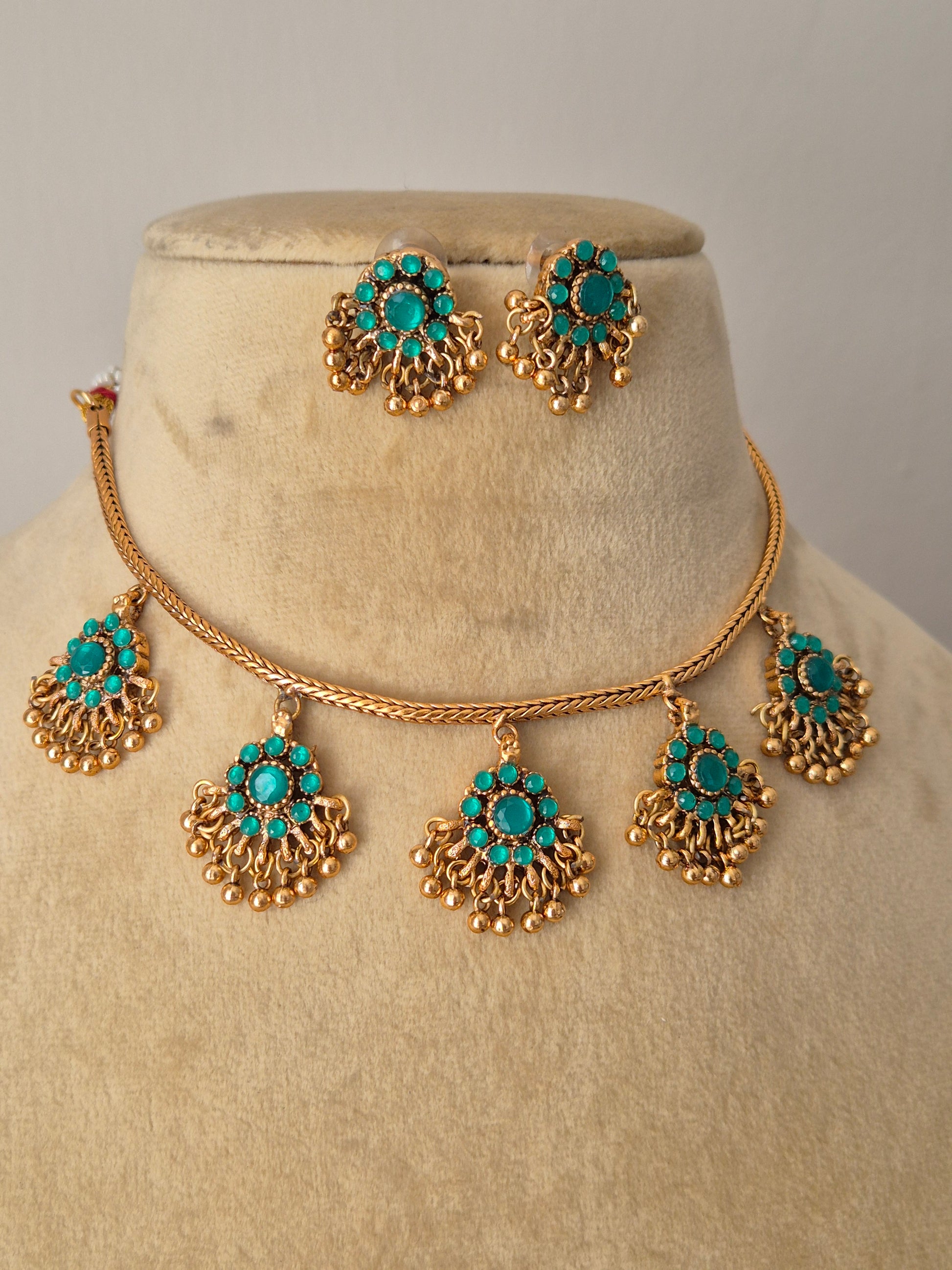 Traditional gold and turquoise necklace set with a classic design, displayed on a beige mannequin bust with delicate dried flowers for a modern Indian aesthetic by naitri.in
