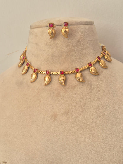 Gold leaf-pattern choker necklace with red stone accents and matching earrings by naitri.in