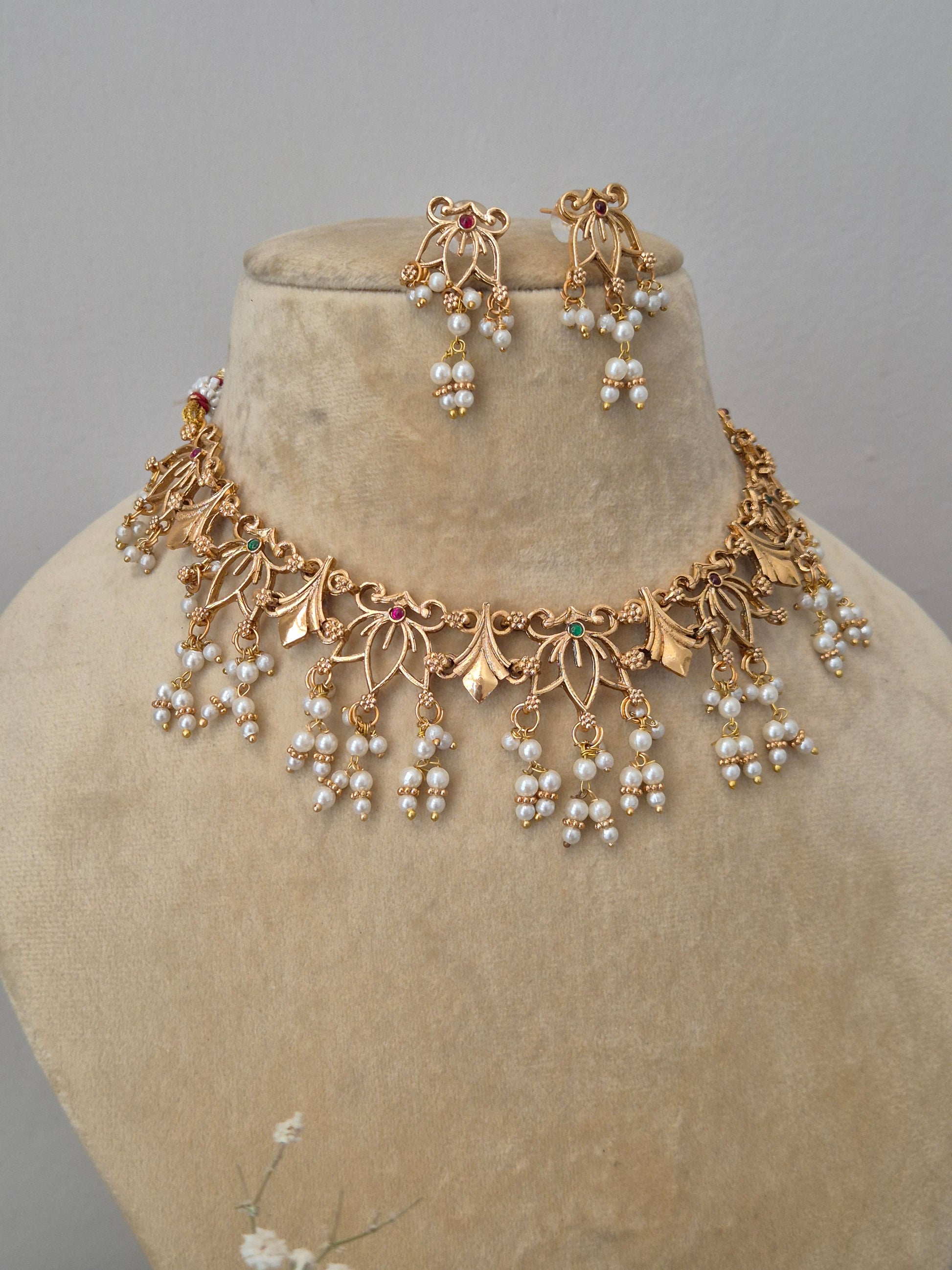 Modern traditional golden choker necklace set featuring intricate metalwork and delicate white pearl beads by naitri.in