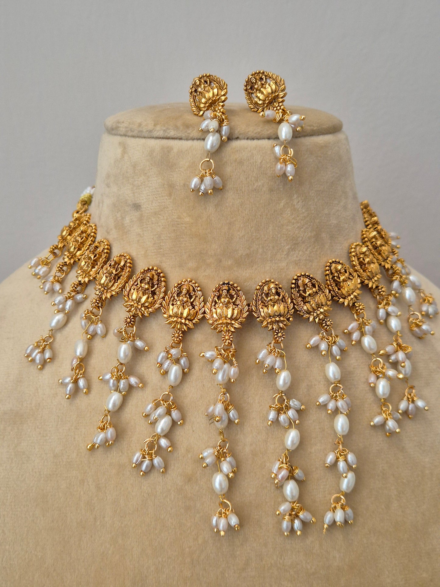 Elegant gold imitation necklace set featuring a choker lined with vertical rows of dangling pearls and matching gold pearl-drop earrings by naitri.in