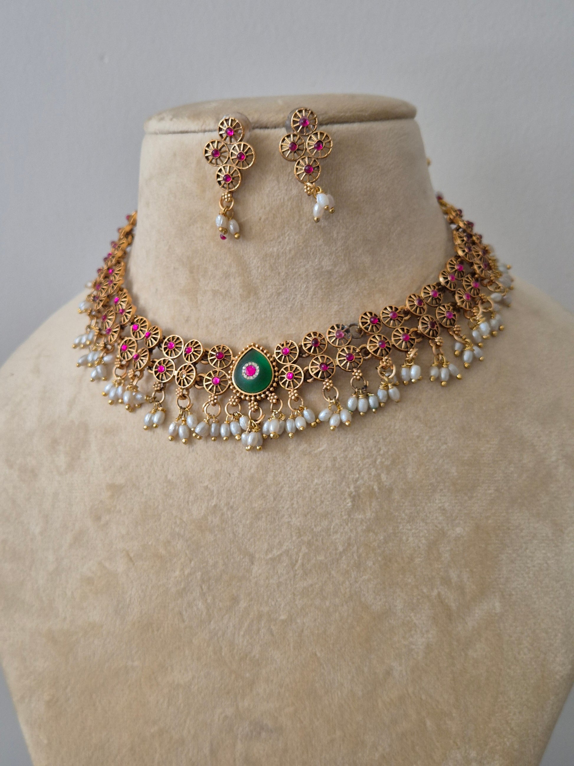 Traditional gold set with pink and green stones and pearl droplets, including matching stud earrings by naitri.in