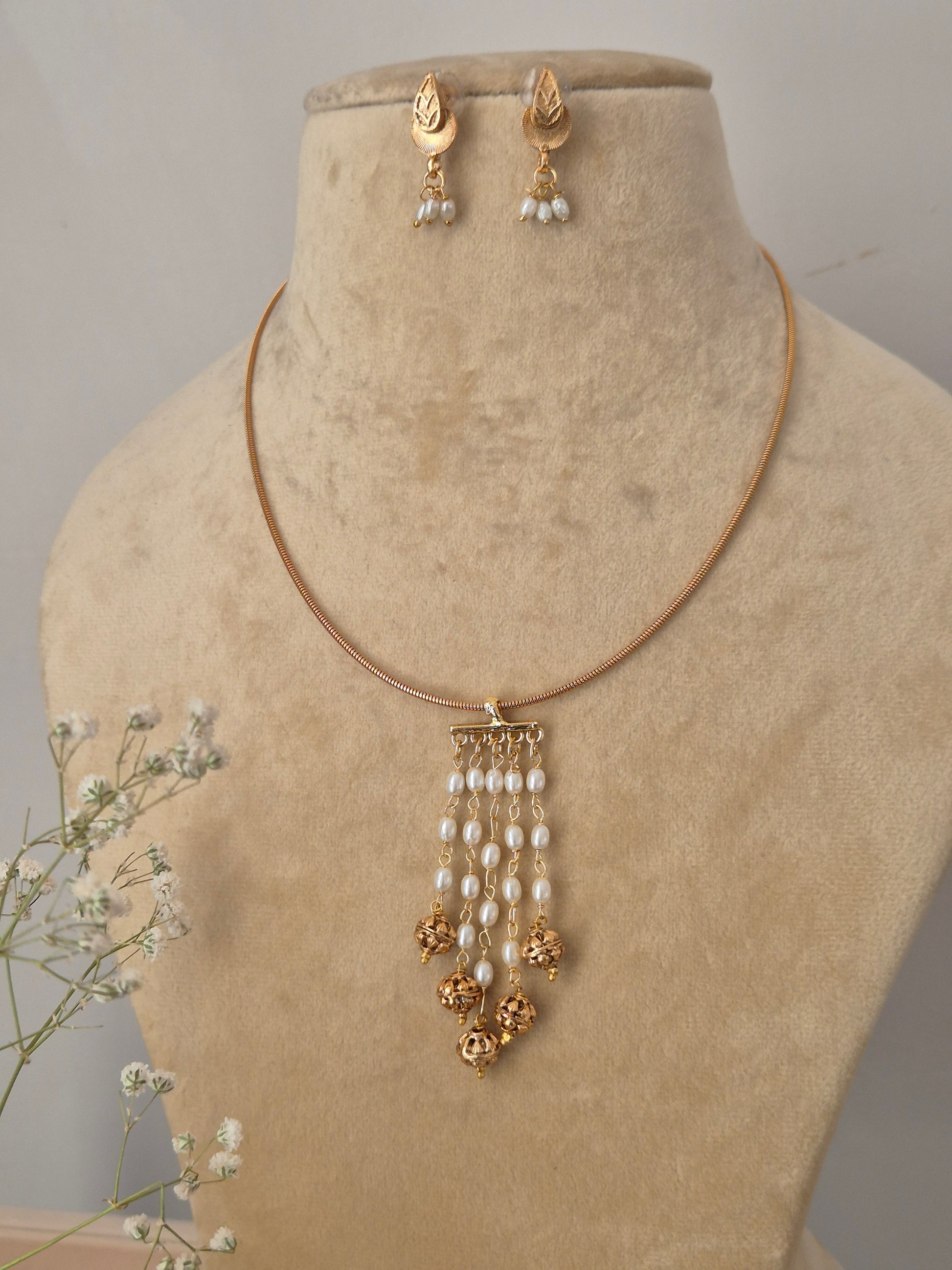 Ethnic gold-plated necklace set with a multi-strand pearl drop pendant and matching stud earrings with pearl accents by naitri.in