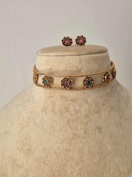 Polished golden brass choker necklace set with intricate metalwork and multi-colored stone accents, part of the Naitri Golden Jewellery collection by naitri.in