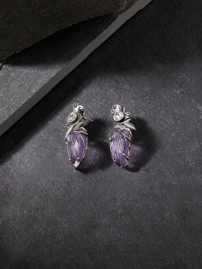 Purple stud earrings with stonework, displayed on a jewelry stand