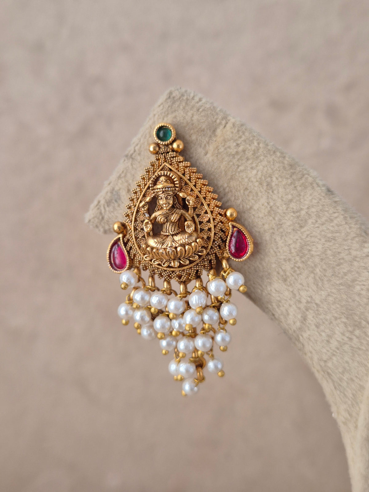 Traditional Indian ethnic earrings with detailed stud designs and cascading pearl droplet fringe against a neutral display by Naitri.in