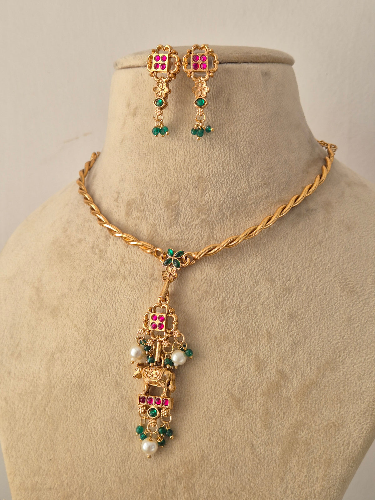 Traditional Indian Gold-Tone Pendant Set showcasing artisanal craftsmanship with vibrant ruby and emerald stone details, a polished gold finish, and matching earrings designed for ethnic festive wear by Naitri.in