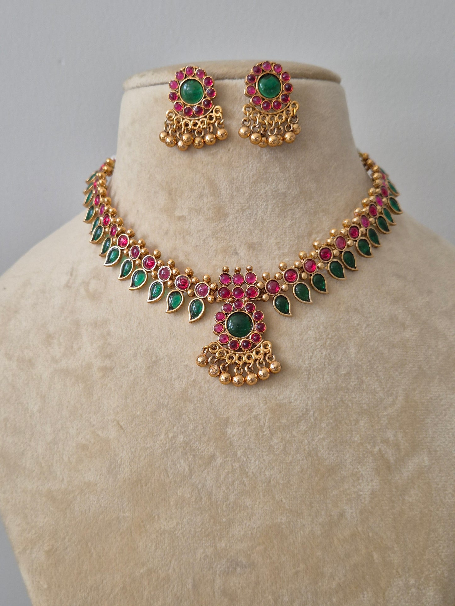 Traditional Indian gold-plated necklace set with green and red stones by naitri.in