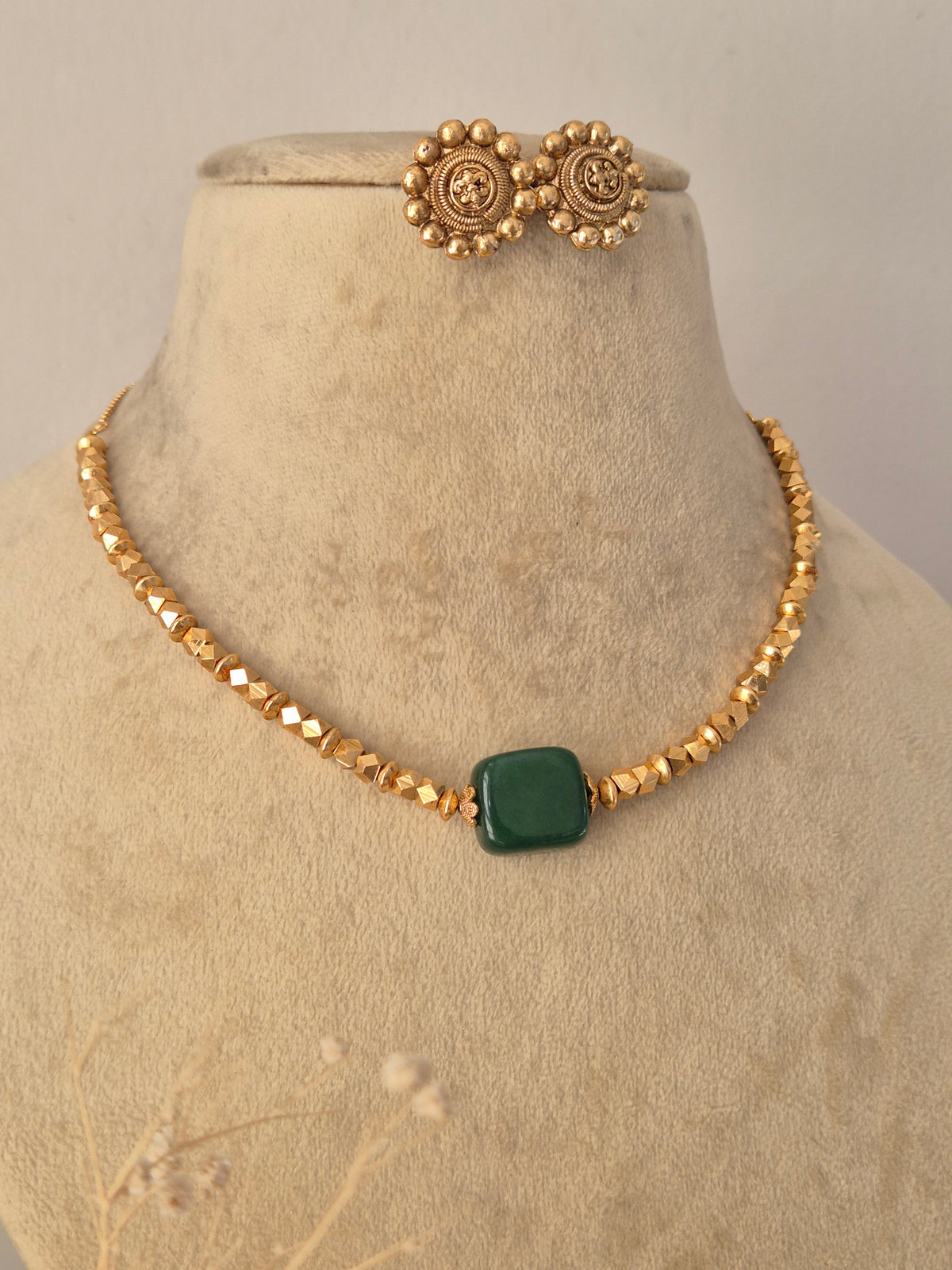 Traditional Indian Minimalist Necklace styled against a neutral background, highlighting the elegant multi-strand golden beads, vibrant green center stone, and sophisticated ethnic craftsmanship by Naitri.in