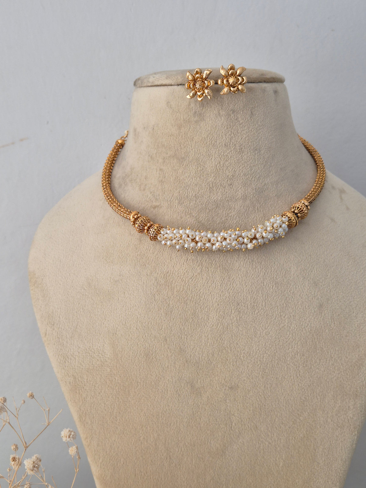 Traditional Indian gold-toned choker necklace set with pearl embellishments and matching earrings by Naitri.in
