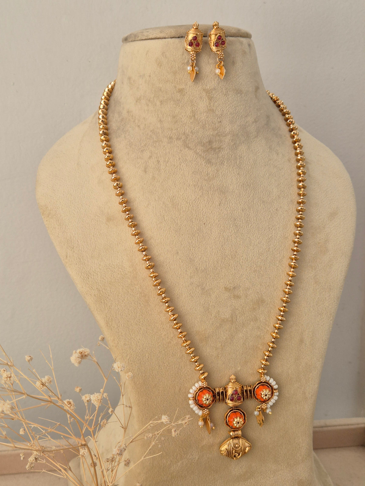 Front view of the Pavitra Necklace Set showcasing the gold temple pendant and matching earrings styled on a jewelry mannequin by Naitri.in