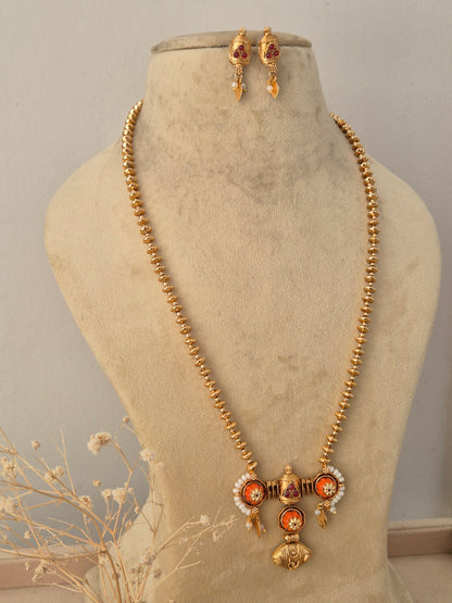 Front view of the Pavitra Necklace Set showcasing the gold temple pendant and matching earrings styled on a jewelry mannequin by Naitri.in