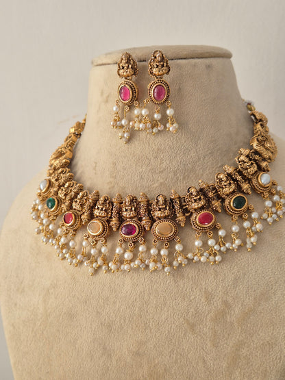 Traditional Indian Ethnic Necklace and Earrings styled against a neutral background, highlighting rich antique gold detailing, vibrant multi-toned stones, and layered pearl accents by Naitri.in