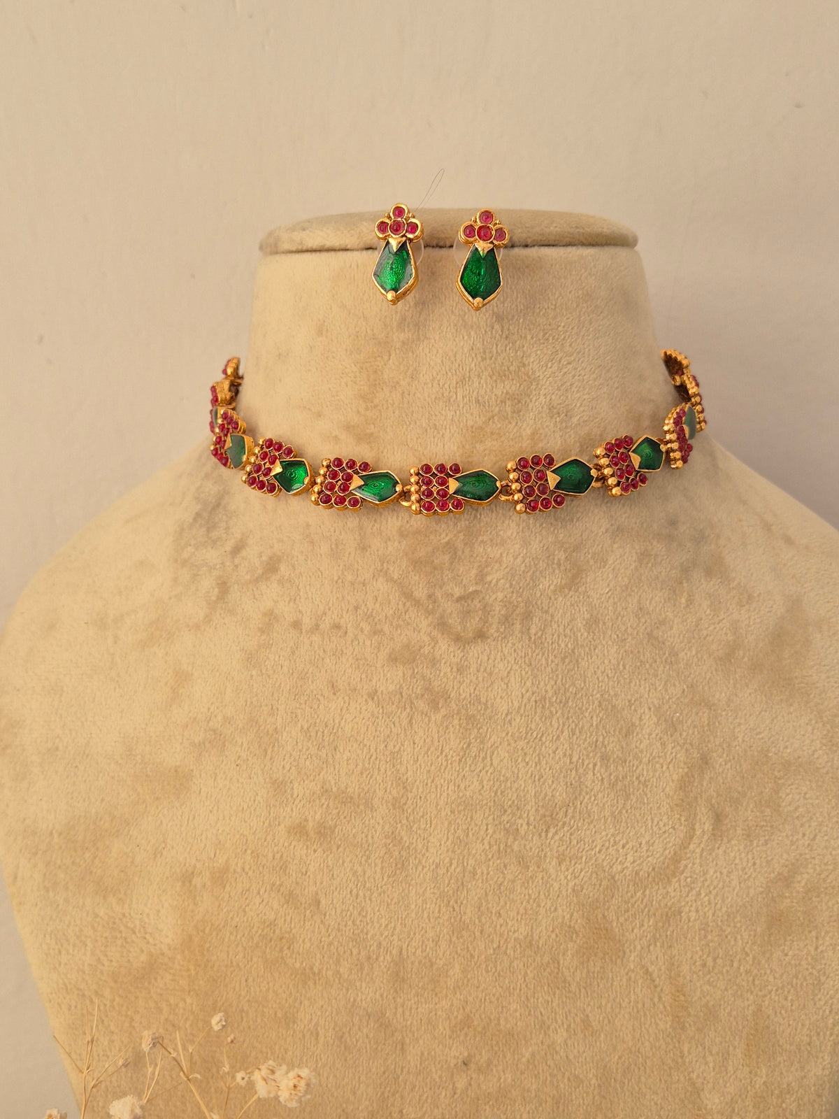 Traditional Indian gold-toned choker necklace with green and pink stone elements, paired with matching teardrop earrings by Naitri.in